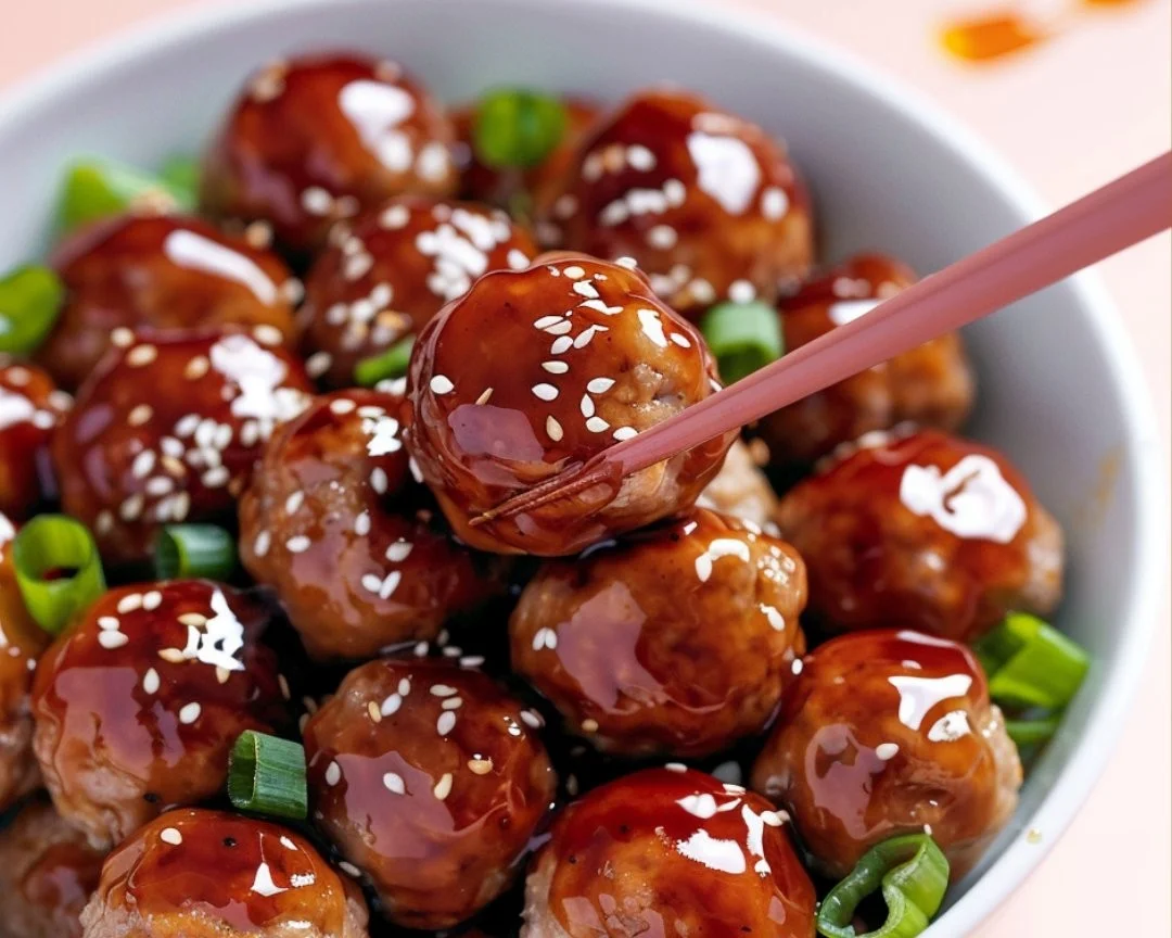 Plate of Asian glazed turkey meatballs garnished with sesame seeds and green onions.