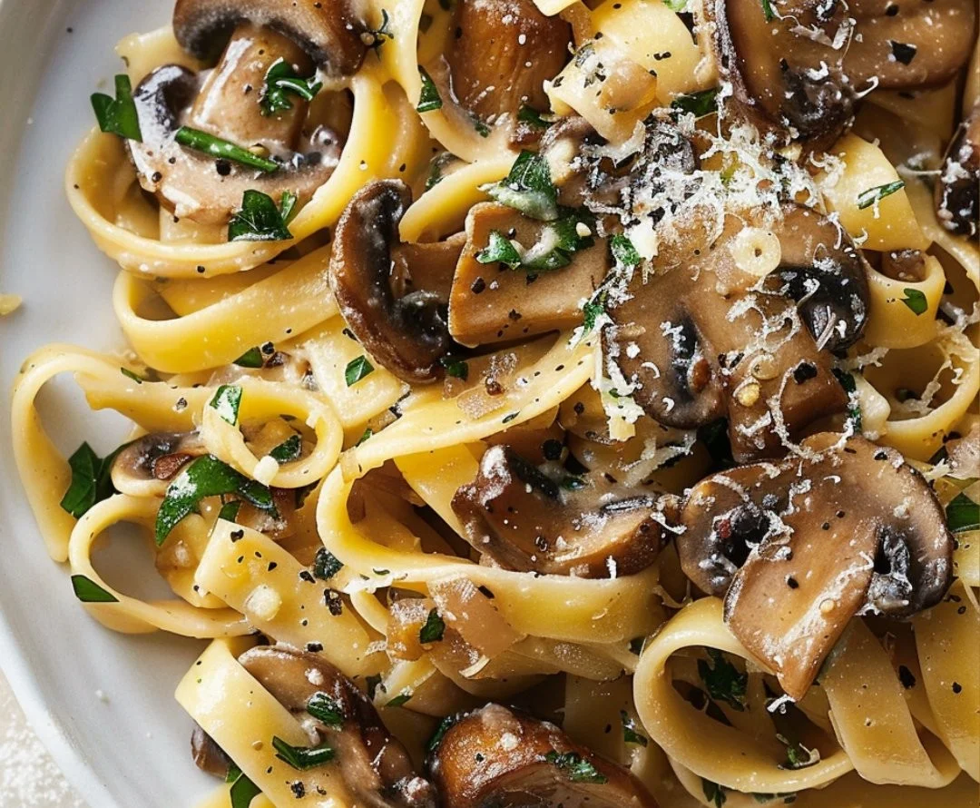 A plate of Garlic Mushroom Pasta garnished with fresh herbs and parmesan cheese.
