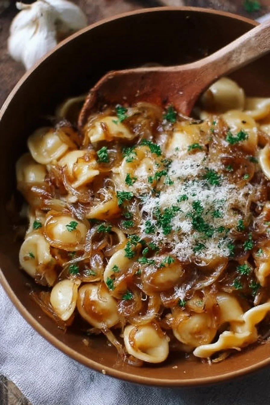 Bowl of comforting French onion pasta topped with melted cheese and herbs