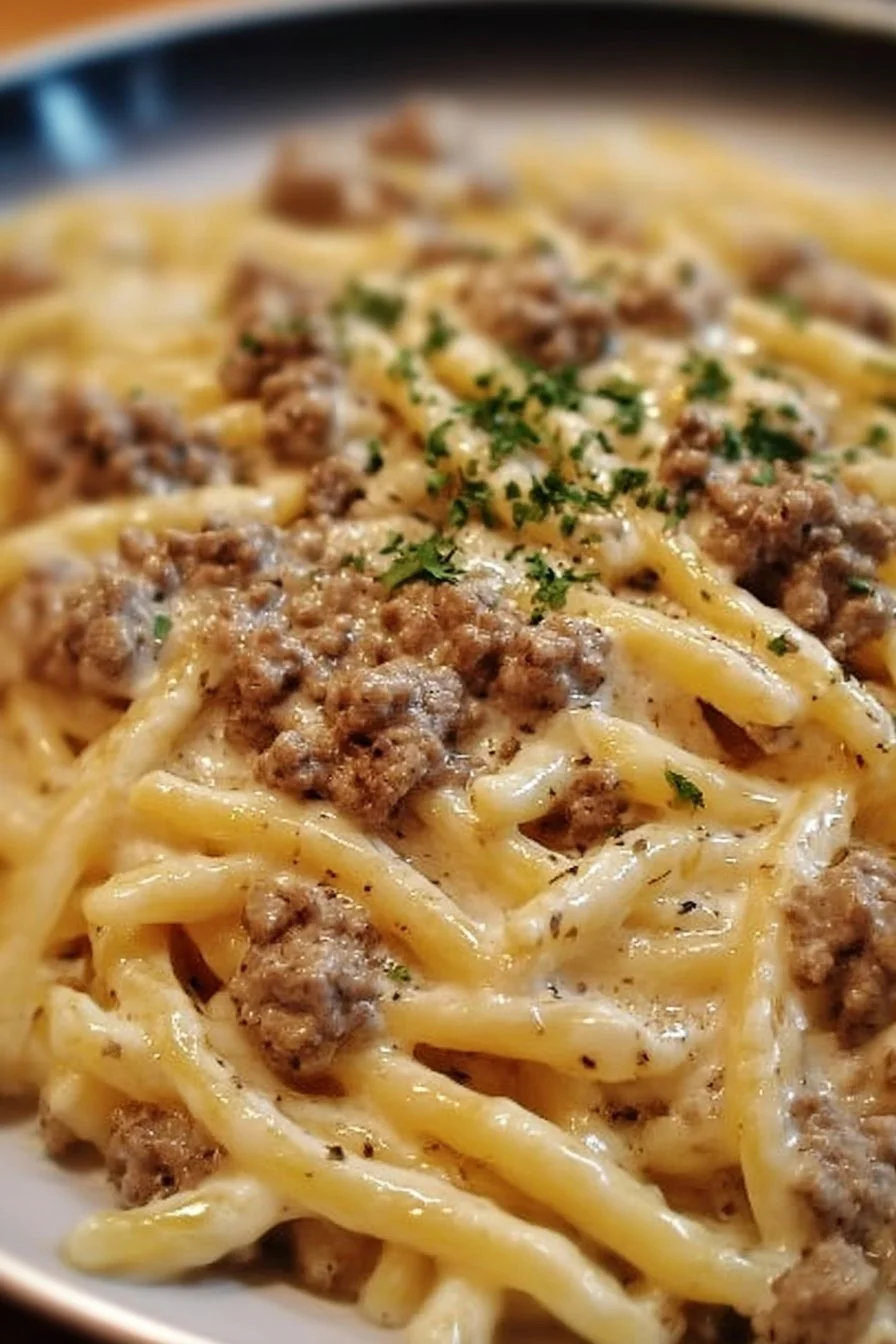 Creamy ground beef alfredo pasta served in a bowl with parsley garnish