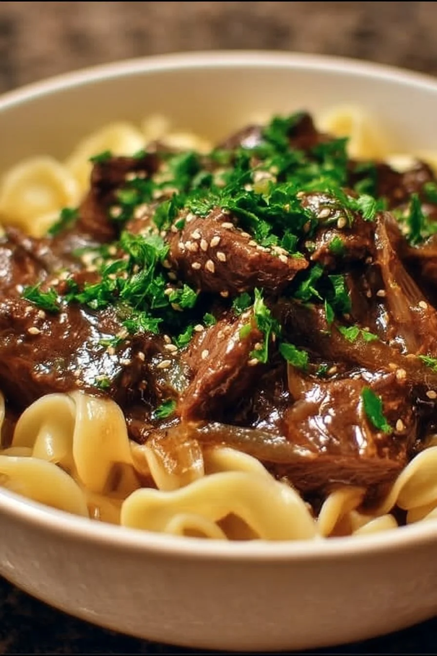 A delicious plate of French Onion Beef Noodles topped with melted cheese.