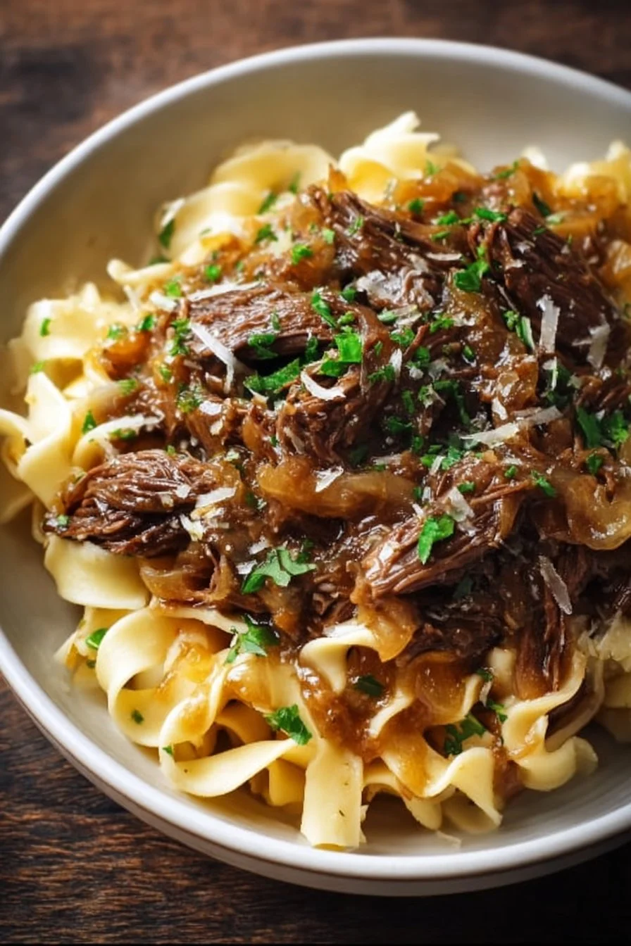 Sizzling French onion beef and noodles in a hearty bowl, garnished with herbs.