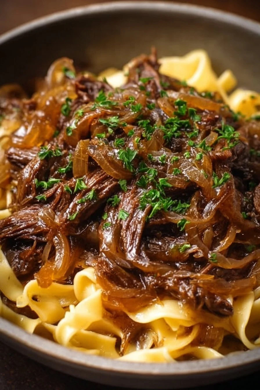Delicious Sizzling French Onion Beef served over noodles in a bowl.