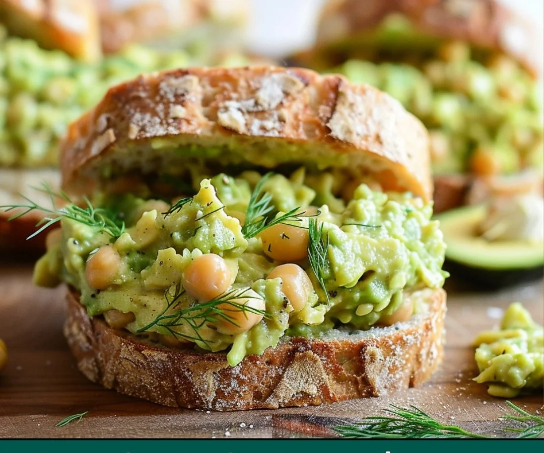 Smashed chickpea avocado dill pickle sandwich on a wooden board