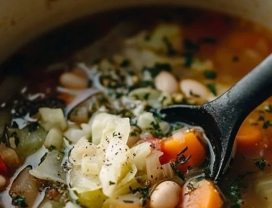 Bowl of warm and hearty cabbage soup garnished with herbs