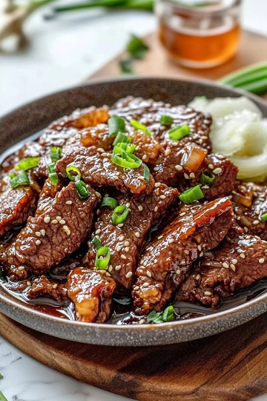 Slow cooker Mongolian Beef dish garnished with green onions and served over rice.
