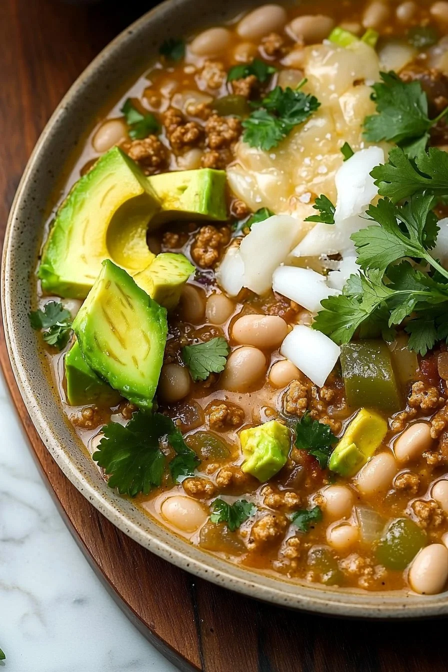 Healthy white turkey chili with avocado and white beans served in a bowl