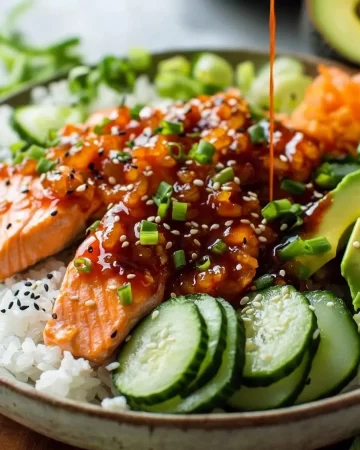 Spicy salmon rice bowl garnished with fresh vegetables and sesame seeds.